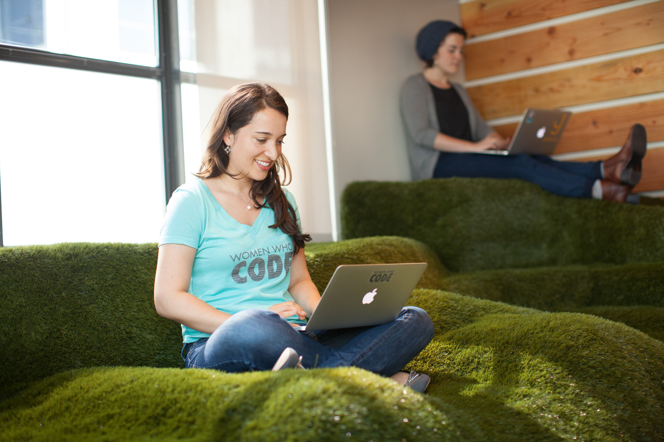 A woman coder works on a laptop in an astro turf cubby at a San Francisco office