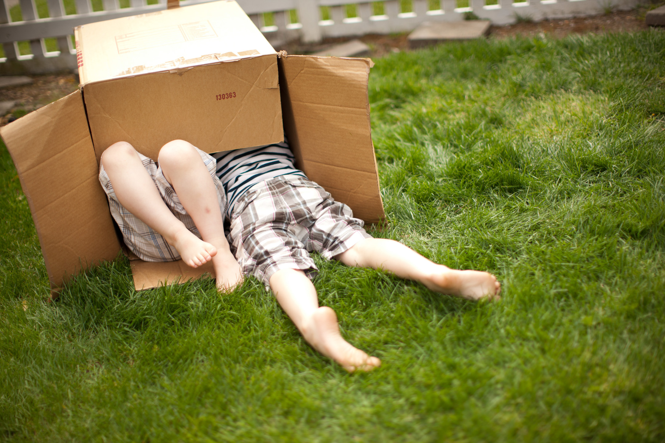 Two boys play in a cardboard box
