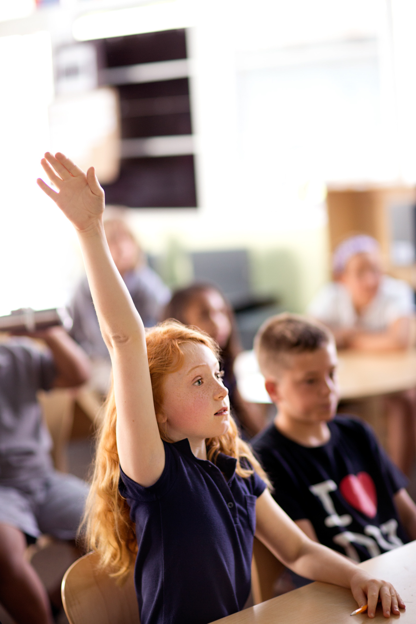 A girl raises her hand in a classroom