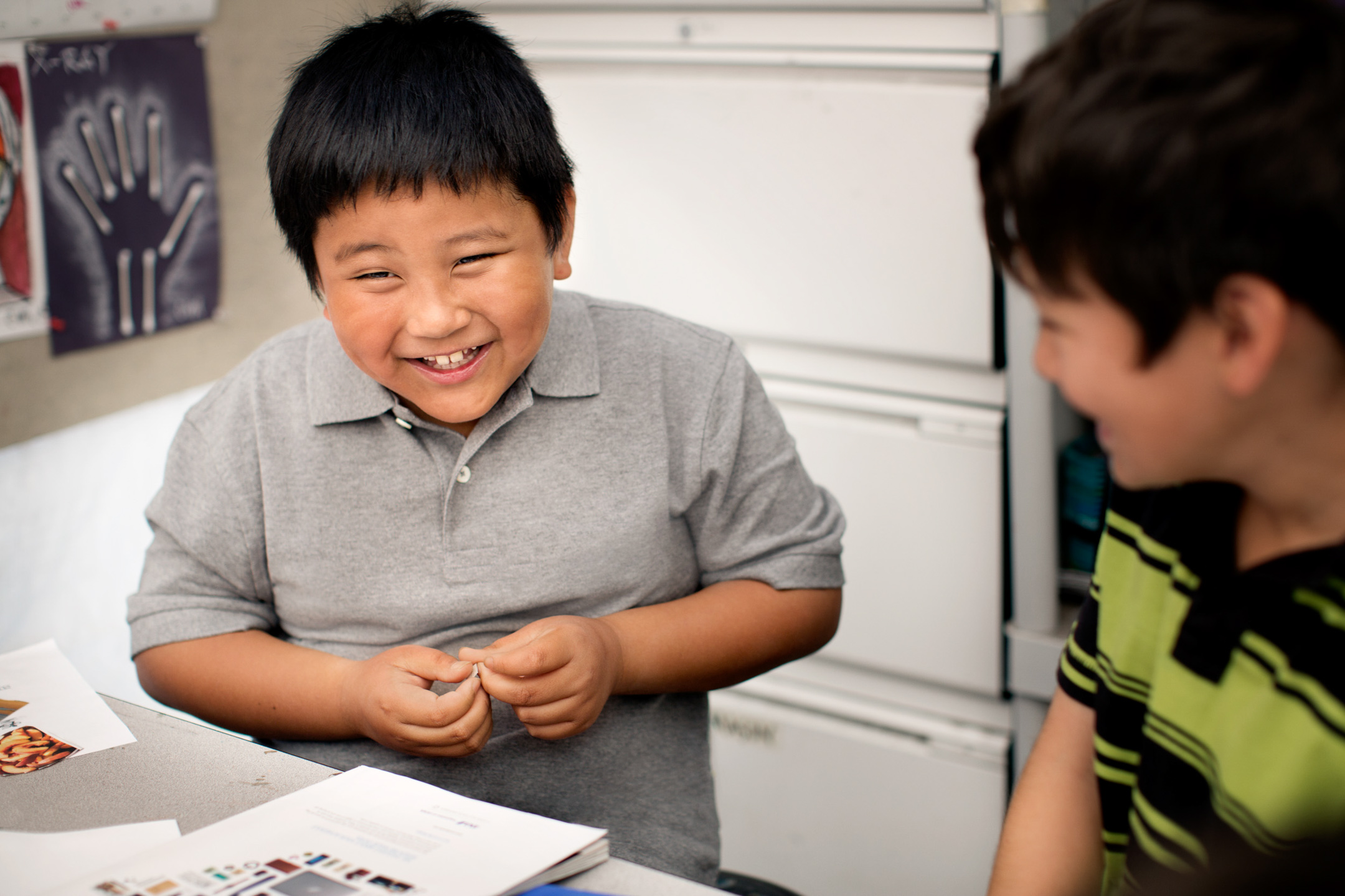 A boy laughs with a classmate during art class at an elementary school
