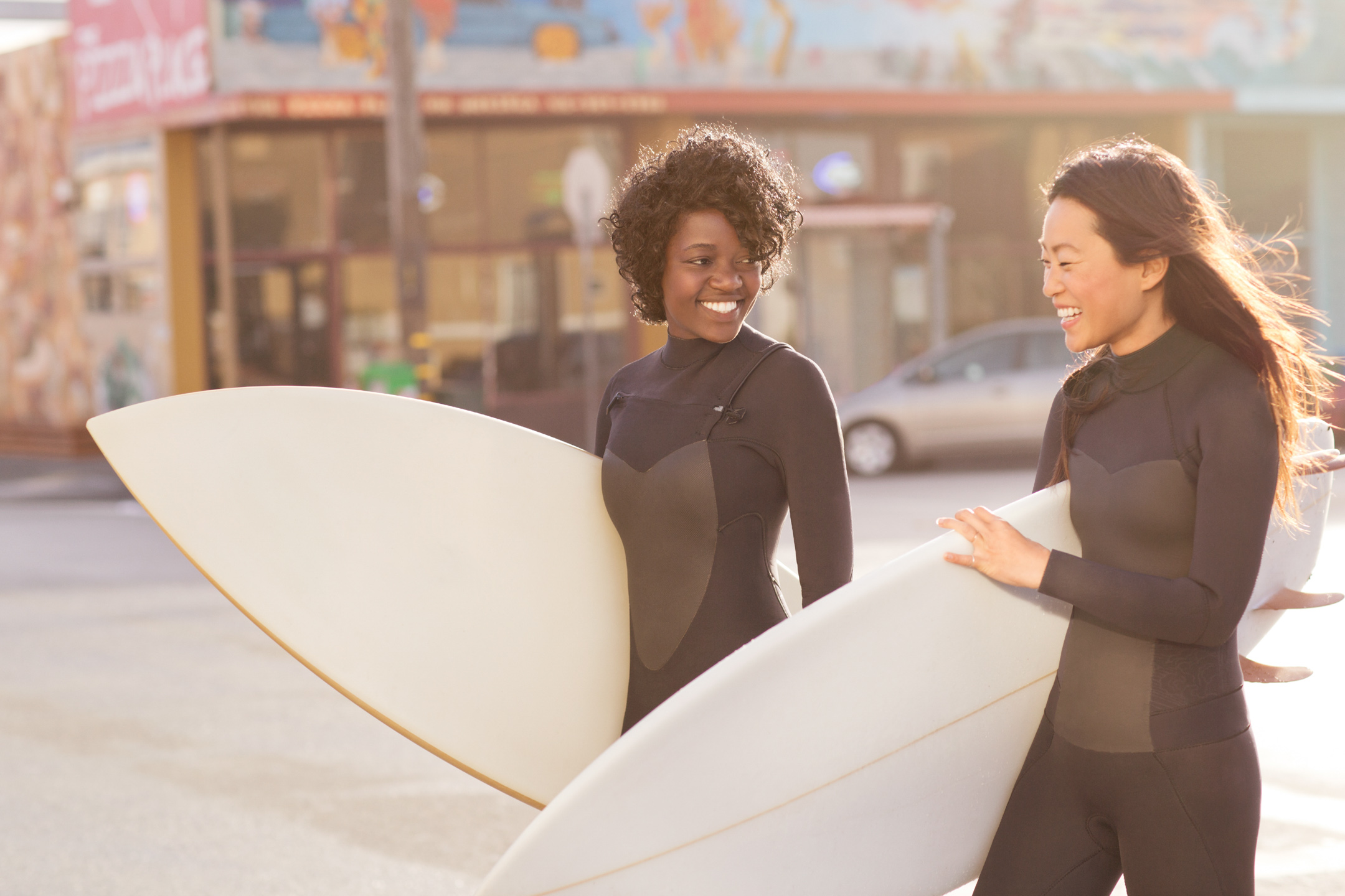 Two women walk through the streets of San Francisco with surf boards, on their way to the beach