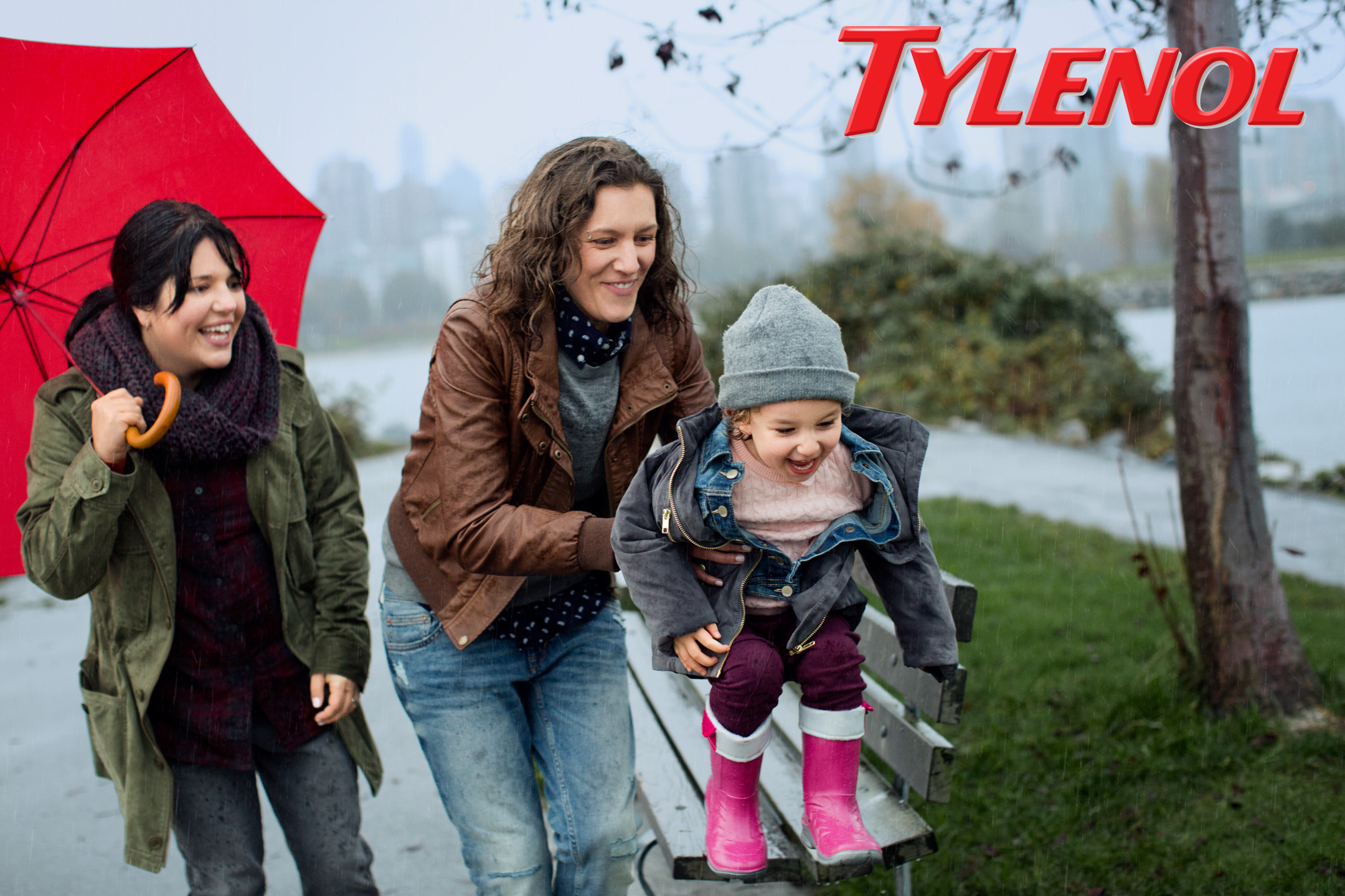 Two women play in the rain with their daughter in a Tylenol Ad Campaign photographed by Lifestyle Photographer Diana Mulvihill